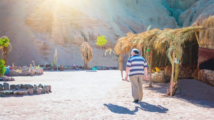 An adult male tourist walks alone among African landscapes, and next to him is a shadow from his wife. The concept of deceased beloved wife