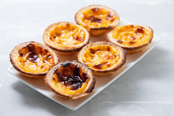 typical portuguese sweets pastel de nata on white dish on ceramic background