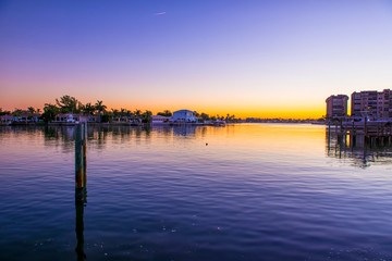 Fototapeta na wymiar A gold and blue sunrise over Florida waterfront homes and marina with reflections in the still water