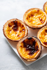 typical portuguese sweets pastel de nata on white dish on ceramic background