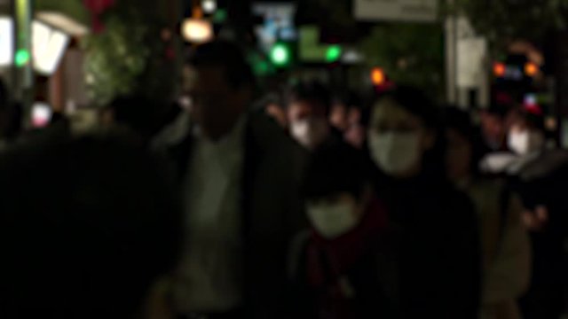 TOKYO, JAPAN - MARCH 2020 : Crowd of people walking down the street in evening rush hour. Many commuters after work. People wearing mask to protect from Coronavirus(COVID-19) or cold. Blurred shot.