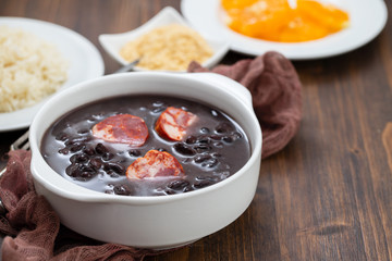 typical brazilian food black beans with smoked sausages in white bowl