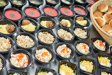 Row of plastic disposable lunch box with healthy natural food. Soups, cream soup, main course with side dish, salads. Food delivery. Lunch in the office.