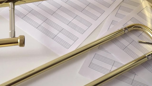 Hand leaving trombone mouthpiece on blank sheet music on table.