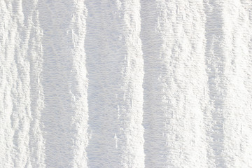 Background, white  texture of Pamukkale calcium travertine in Turkey, vertical stripes, top view.