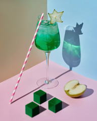 Evening cocktail with apple stands on color backgrounds
