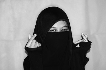 Close up view of Pretty lady woman girl wear hijab jilbab niqab kerudung niqaab scarf cover face and only show visible look of her beauty eyes. Fit for put design life image. Black white  with grain t