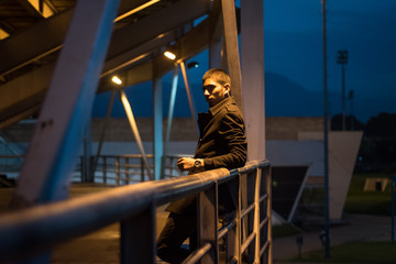 A young man in a park surrounded by a  steel structure, with the mountains as background 