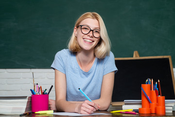 Smiling girl student or woman teacher portrait on green wall blackboard background. Portrait of...