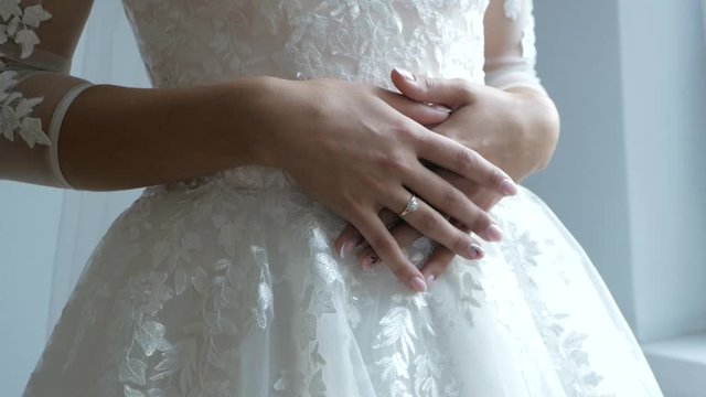 Bride's morning. Hands of a bride close-up lie on a beautiful white wedding dress.