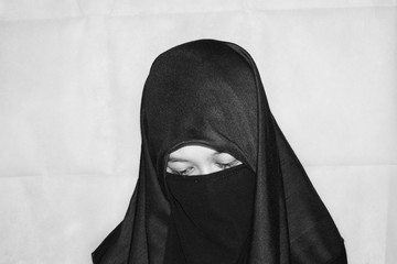 Naklejka premium Close up view of Pretty lady woman girl wear hijab jilbab niqab kerudung niqaab scarf cover face and only show visible look of her beauty eyes. Fit for put design life image. Black white with grain t