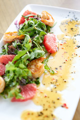 Fresh salad with grilled shrimps, slice grapefruit and arugula salad and spicy fried prawns. Restaurant menu, natural and organic food concept.