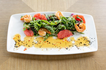 Fresh salad with grilled shrimps, slice grapefruit and arugula salad and spicy fried prawns. Restaurant menu, natural and organic food concept.