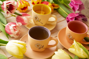 Fototapeta na wymiar Morning concept. Cups of tea and beautiful colorful tulips. Romantic vintage image with morning sun light
