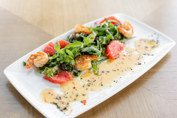 Fresh salad with grilled shrimps, slice grapefruit and arugula salad and spicy fried prawns. Restaurant menu, natural and organic food concept.