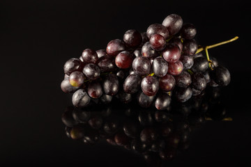 A bunch of black grapes closeup on a black glass table