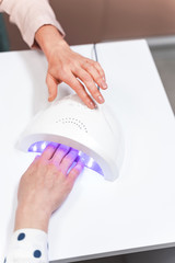 Competent manicure master turning on timer on lamp