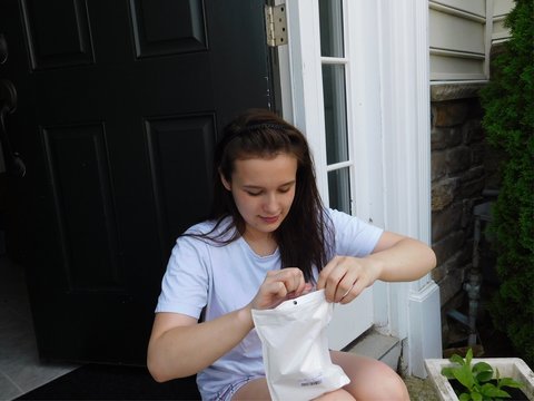 High Angle View Of Teenage Girl Opening Package While Sitting On Floor Against Door