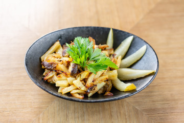 Roasted Potato country style with pickled cucumber in black bowl on wooden background