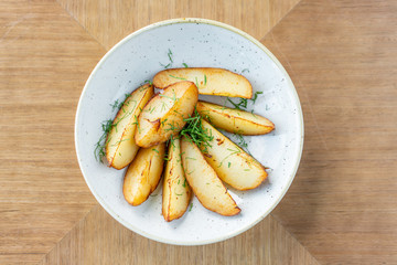 Roasted Potato country style with dill in white bowl on wooden background