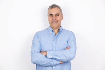 adult handsome man with grey hair wearing blue shirt standing in hand on hand pose on isolated white background, looks confiden