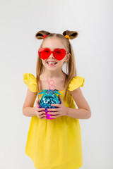 happy child girl in sunglasses holding a glass with a cocktail on a white background isolate