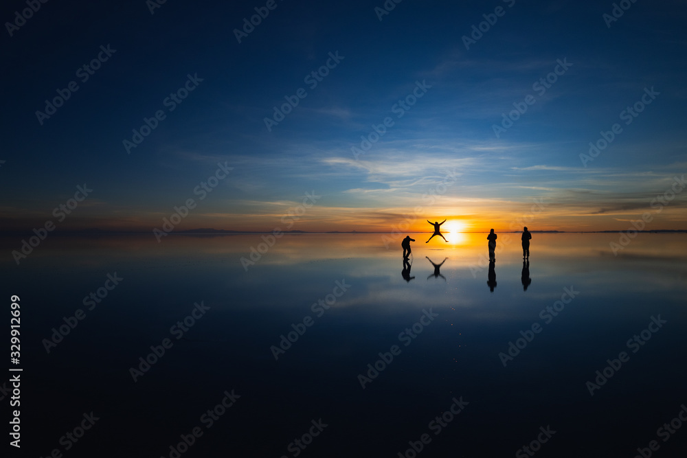 Wall mural uyuni salt flat, bolivia, south america - silhouettes of tourists taking photos at sunrise having fu