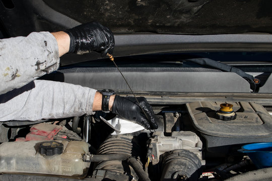 Close Up Of Man's Hands Wearing Latex Gloves For Checking The Oil Dipstick During A DIY At Home Oil Change