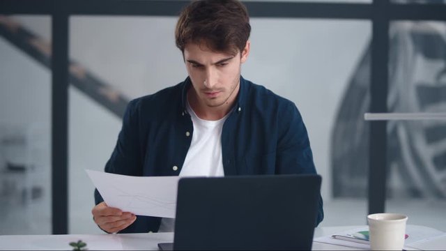 Focused businessman reading document carefully. Concentrated man looking papers