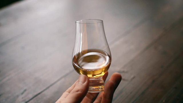 HD footage of a hand holding and analyzing a Glencairn whisky glass.