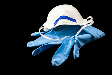 Blauer Gummihandschuh und Mundmaske freigestellt auf schwarzem Hintergrund
