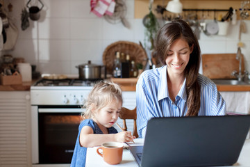 Working mom works from home office with kid. Happy mother and daughter. Woman and cute child using...