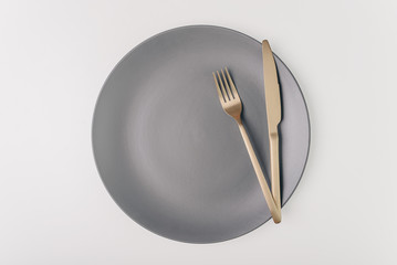 Fork and knife on a empty grey plate isolated on white bacground