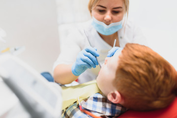 Little boy having his teeth examined by a dentist