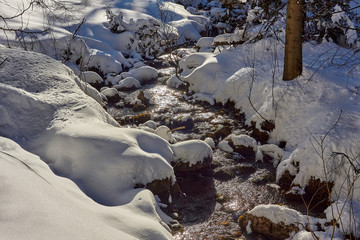 Snow covering stones in Malolacki Stream (Małołącki Potok) in Mala Laka Valley (Dolina Małej Łąki) nearby Zakopane in Tatra mountains.