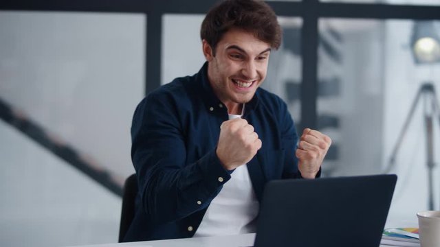 Surprised man getting good news on laptop. Cheerful businessman winning project.