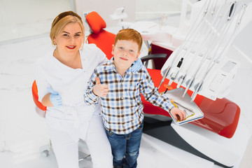 Dentist wearing mask. Red-haired child dentist wearing mask examining cute boy