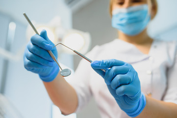 Portrait of a dentist holding dental instruments in his hands in the clinic close-up