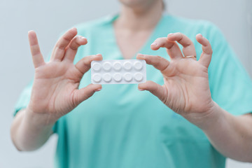 doctor propose white blister with tablets or pills to patient. Hands holding digital medicines closeup shot. Shallow depth of field with focus on thermometer. coronavirus disease treatment