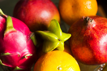 A lot of tropical fruits in a glass vase. Exotic fruits: averrhoa carambola, Pitahaya, Mango,...