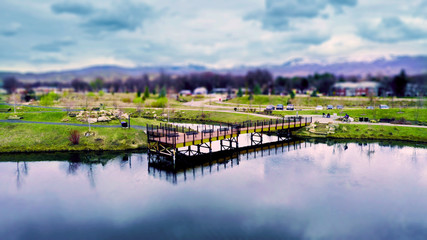 Fototapeta na wymiar Dock Reflection in Pond with Grass & Mountain Background