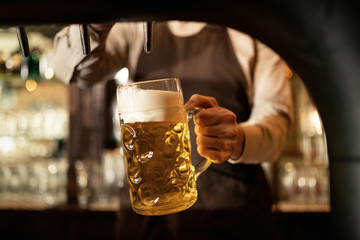 Close-up of bartender pouring draft beer in a glass.
