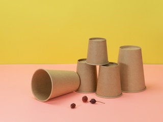 Disposable cups and berries of wild rose on yellow and pink background.