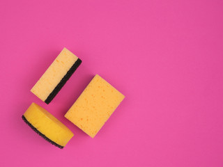 Different sponges for washing dishes and cleaning on a pink background.