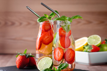 Refreshing drink or water with strawberry, citrus fruits lemon, lime and basil in mason jar with reusable metal straws. Healthy lemonade drink in glass jar, zero waste concept, sustainable lifestyle