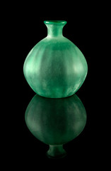 Green frosted glass vase with reflections is isolated on a black background.