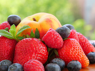 Pile of ripe summer fruits and berries over an outdoor table