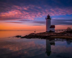 Sunset reflections at Annisquam Lighthouse with sail boat - Gloucester, Massachusetts.