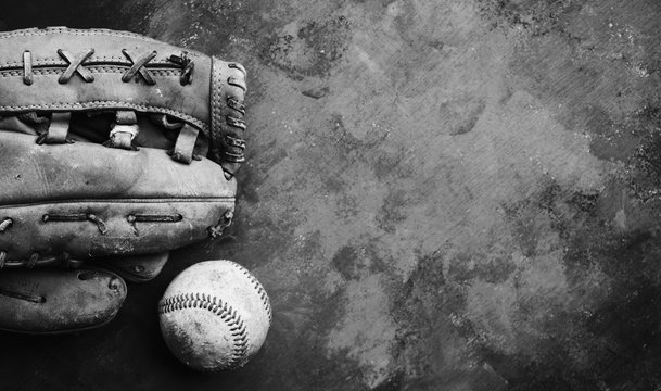 Baseball glove and ball on texture background in black and white, copy space for sport.
