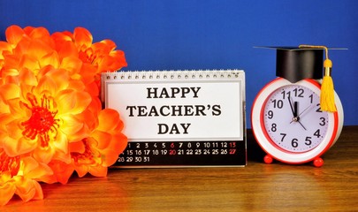 Happy teacher's day -greeting inscription on the calendar and gift flowers. Teacher's day is a professional holiday for school employees.